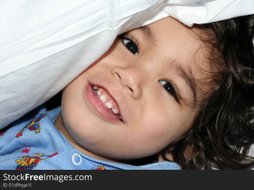 Little boy peeking under pillow