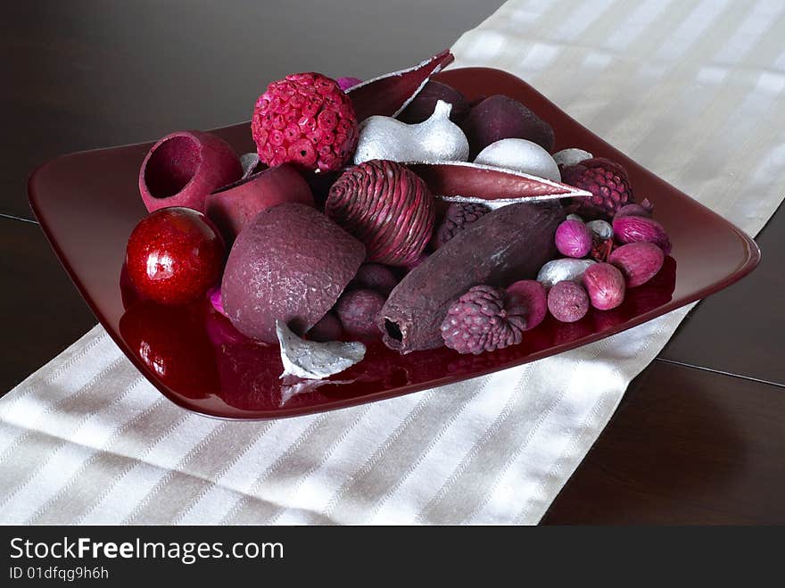 Red potpourri arrangement on glass plate and fabric table runner