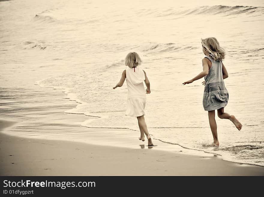 Two young girls play in the waves at the beach. Cross-processed color for dramatic effect. Lots of room for copy. Two young girls play in the waves at the beach. Cross-processed color for dramatic effect. Lots of room for copy.