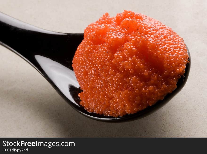 Red russian caviar in a black spoon