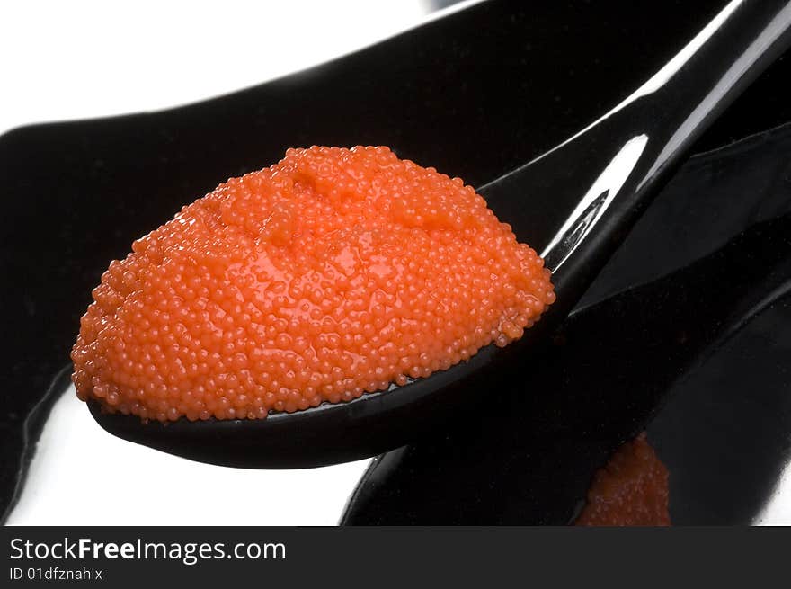 Red russian caviar in a black spoon