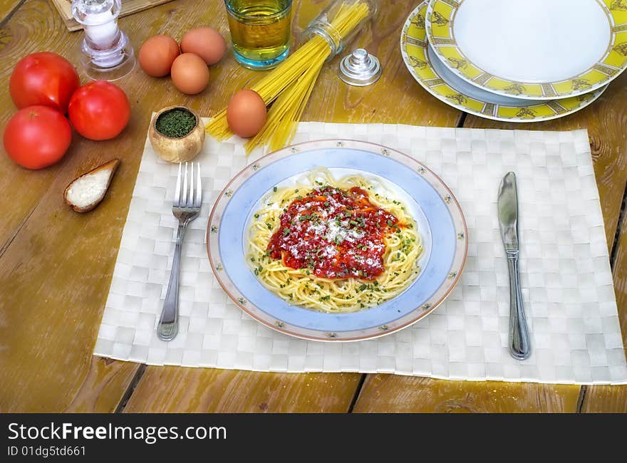 Spaghetti and tomato sauce on wooden desk