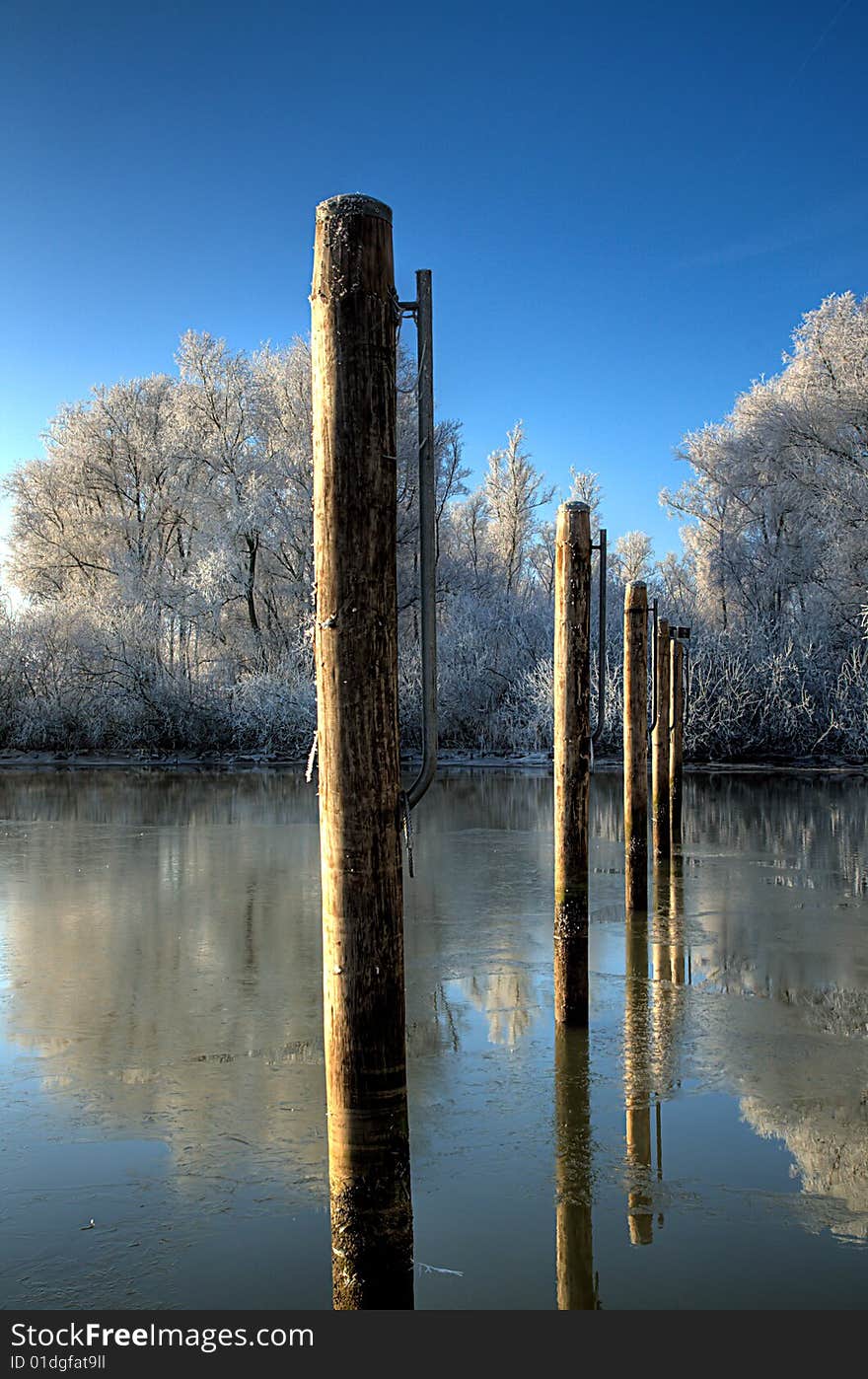 Winter scene with poles in the icy water