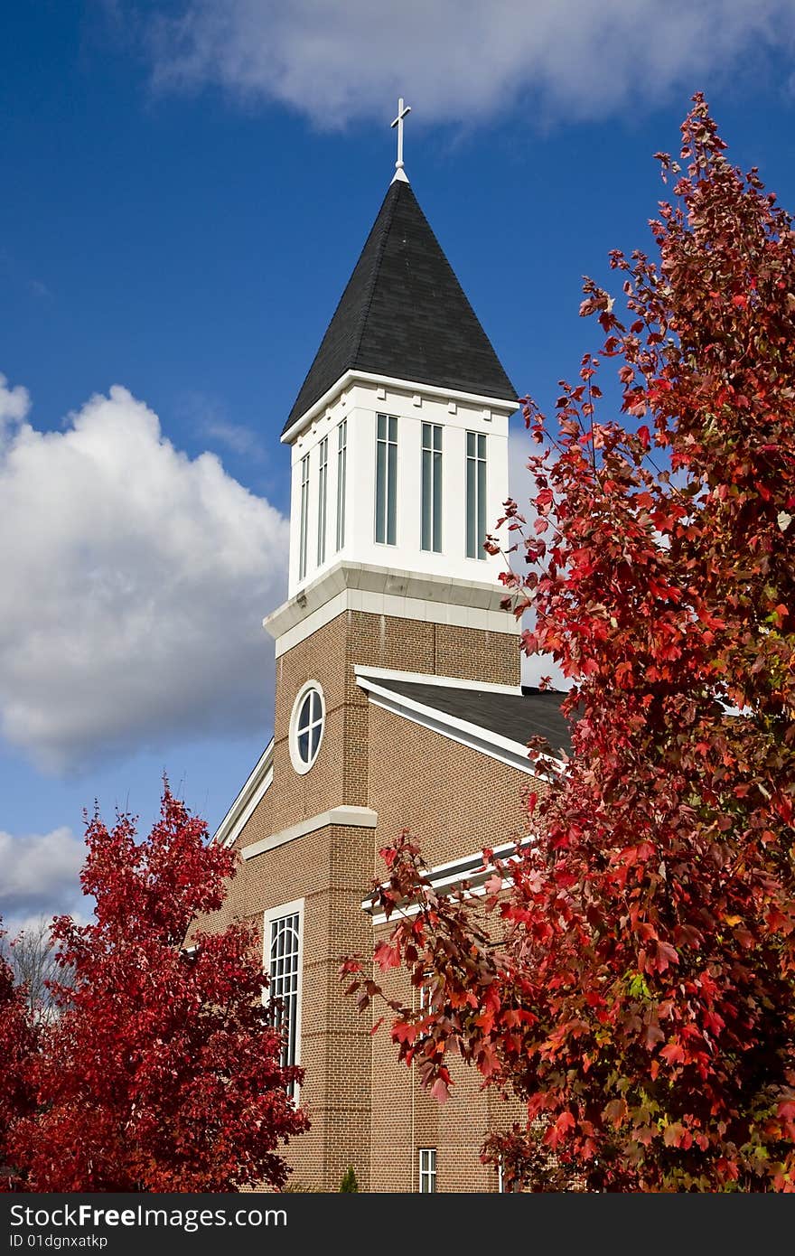 A modern brick church with autumn trees and partly cloudy sky. A modern brick church with autumn trees and partly cloudy sky