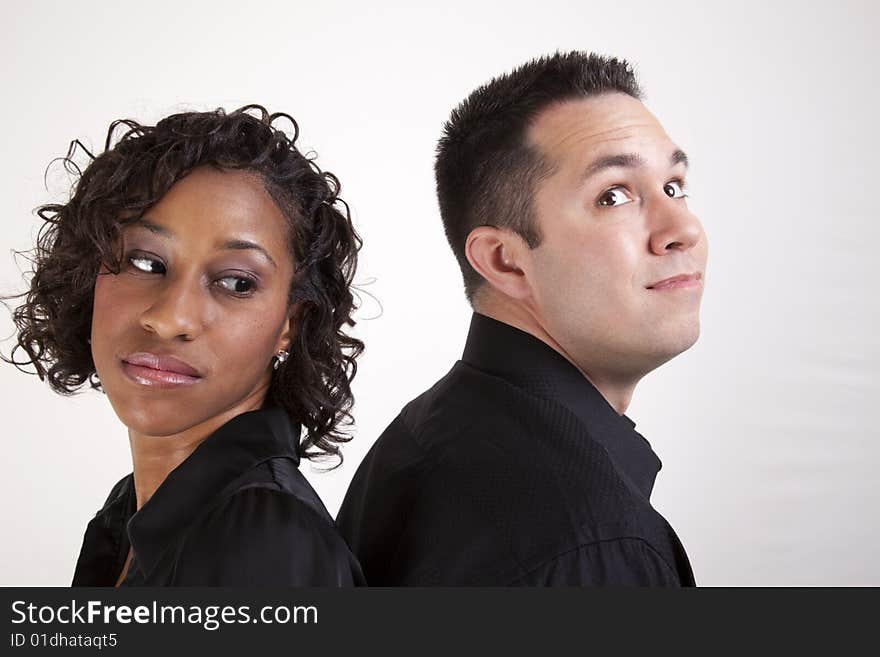 Woman looking over her shoulder at a man flashing an innocent look. Couple back to back. Woman looking over her shoulder at a man flashing an innocent look. Couple back to back.