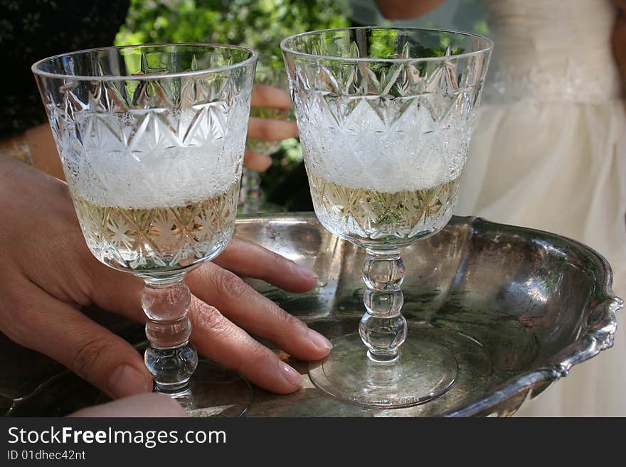 Two glasses of champagne are on a silver tray. Two glasses of champagne are on a silver tray.