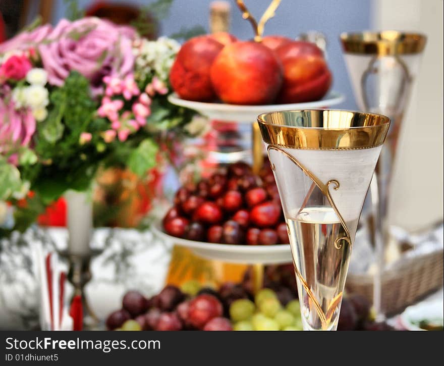 Glass with champagne against a bouquet and fruit. Glass with champagne against a bouquet and fruit