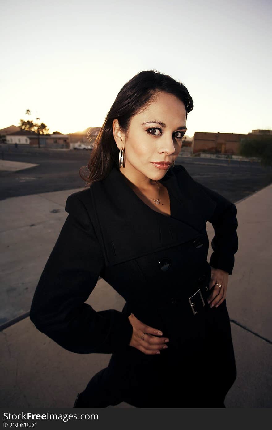 Beautiful woman wearing black trenchcoat at sunset. Beautiful woman wearing black trenchcoat at sunset