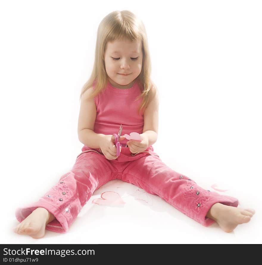 Pretty small girl is cutting paper heart shape