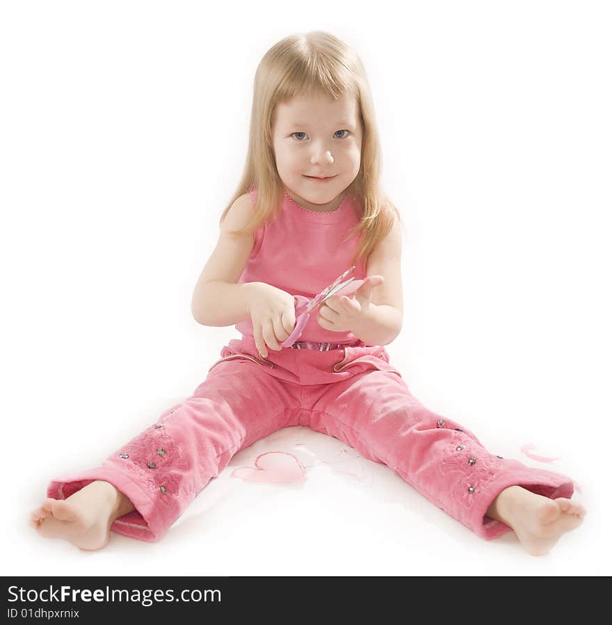 Pretty small girl in red is cutting paper heart shape