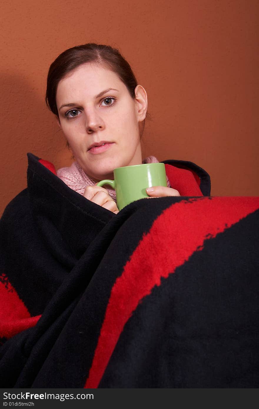 A young sick woman with a cup of tea in her hand. A young sick woman with a cup of tea in her hand.