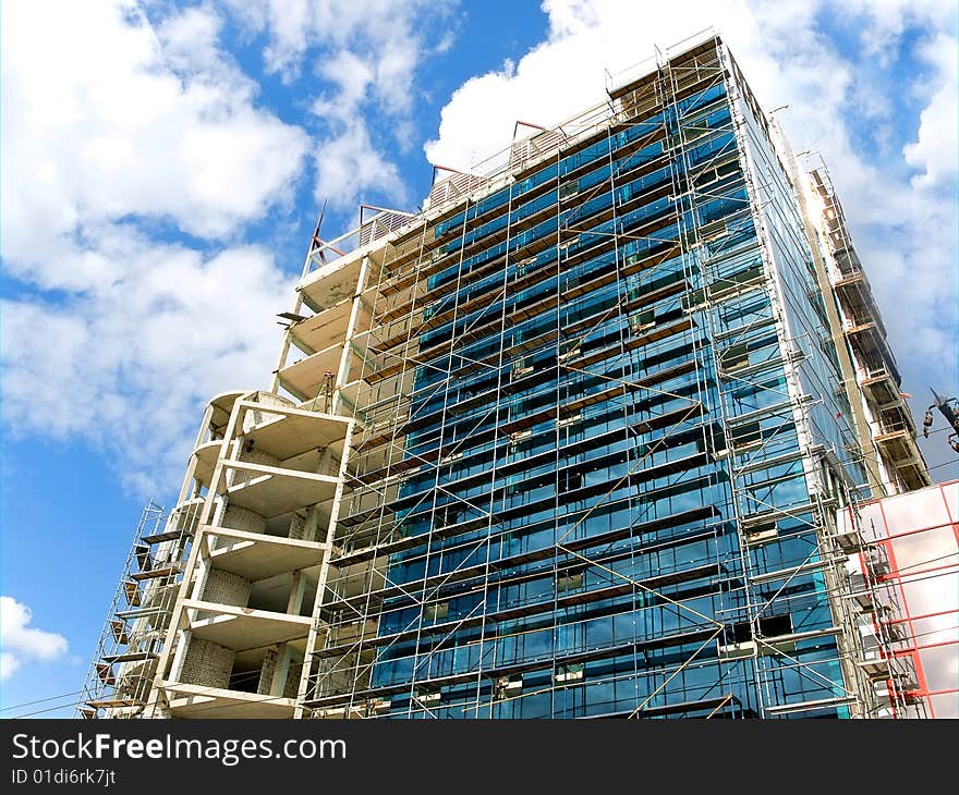 High building of glass and concrete on a blue sky background. 
under construction. High building of glass and concrete on a blue sky background. 
under construction