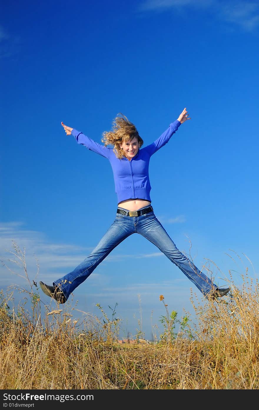 The girl jumps in the field against the sky. The girl jumps in the field against the sky