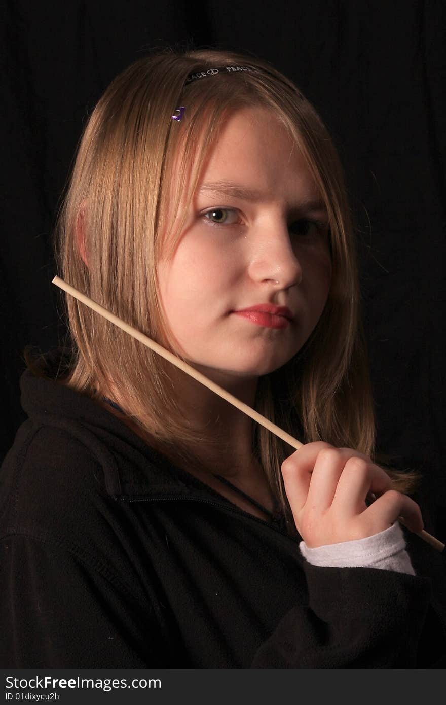 Teen age girl holding a wand just below her face. Teen age girl holding a wand just below her face