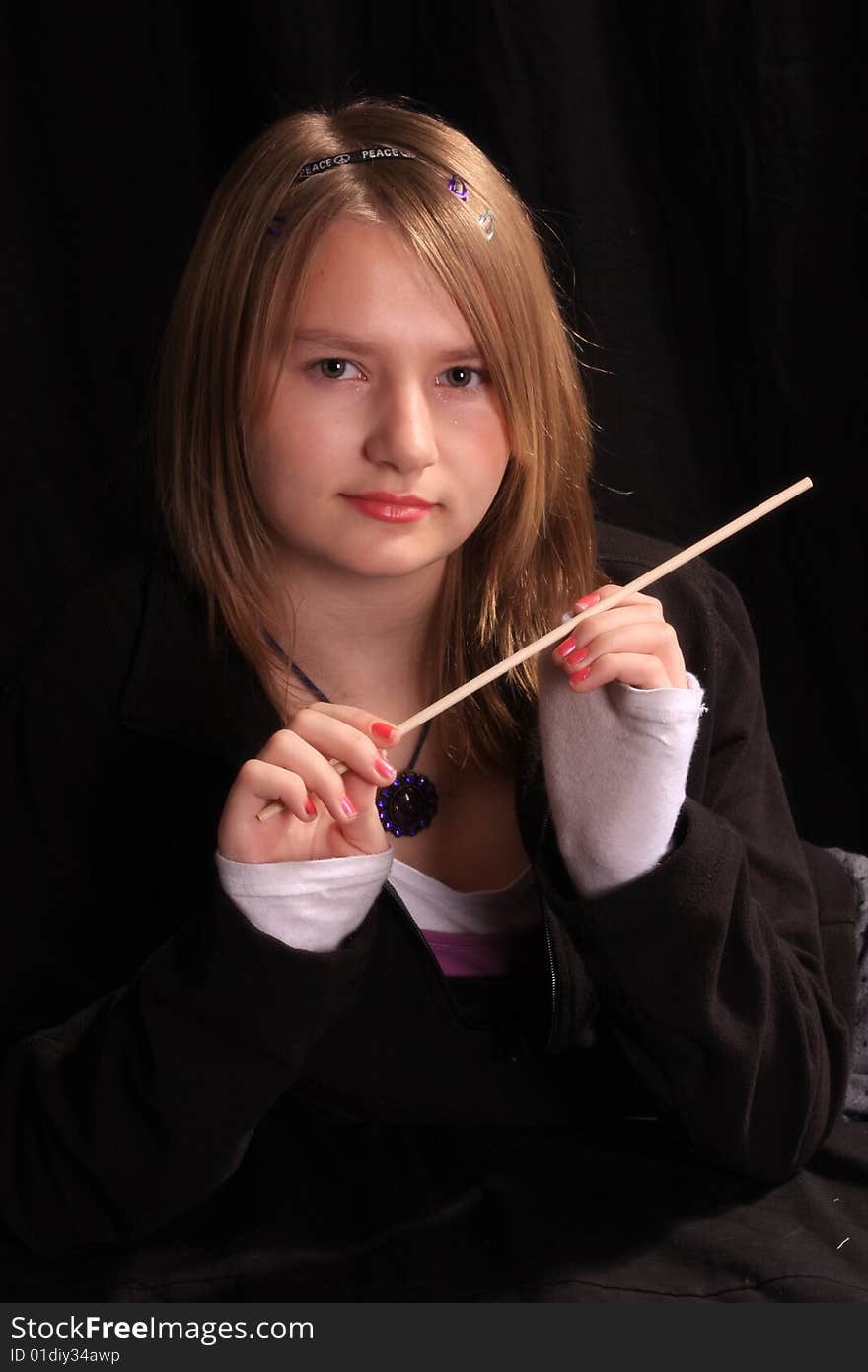 Teen age girl holding a wand upto to her face. Teen age girl holding a wand upto to her face.