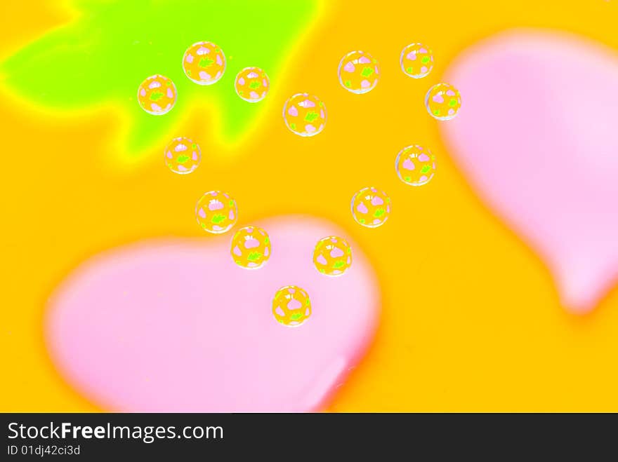 Water drops in the form of heart on a multi-coloured celebratory background