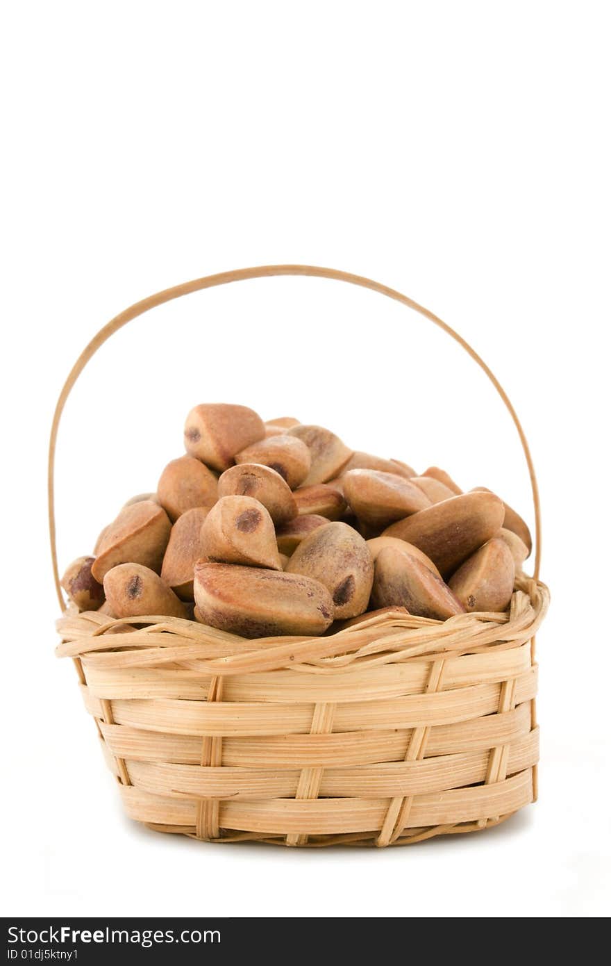 The crude pine nuts in a basket on a white background