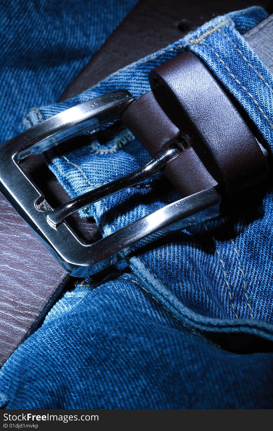 Close-up of  leather belt with steel buckle lying on jeans. Close-up of  leather belt with steel buckle lying on jeans