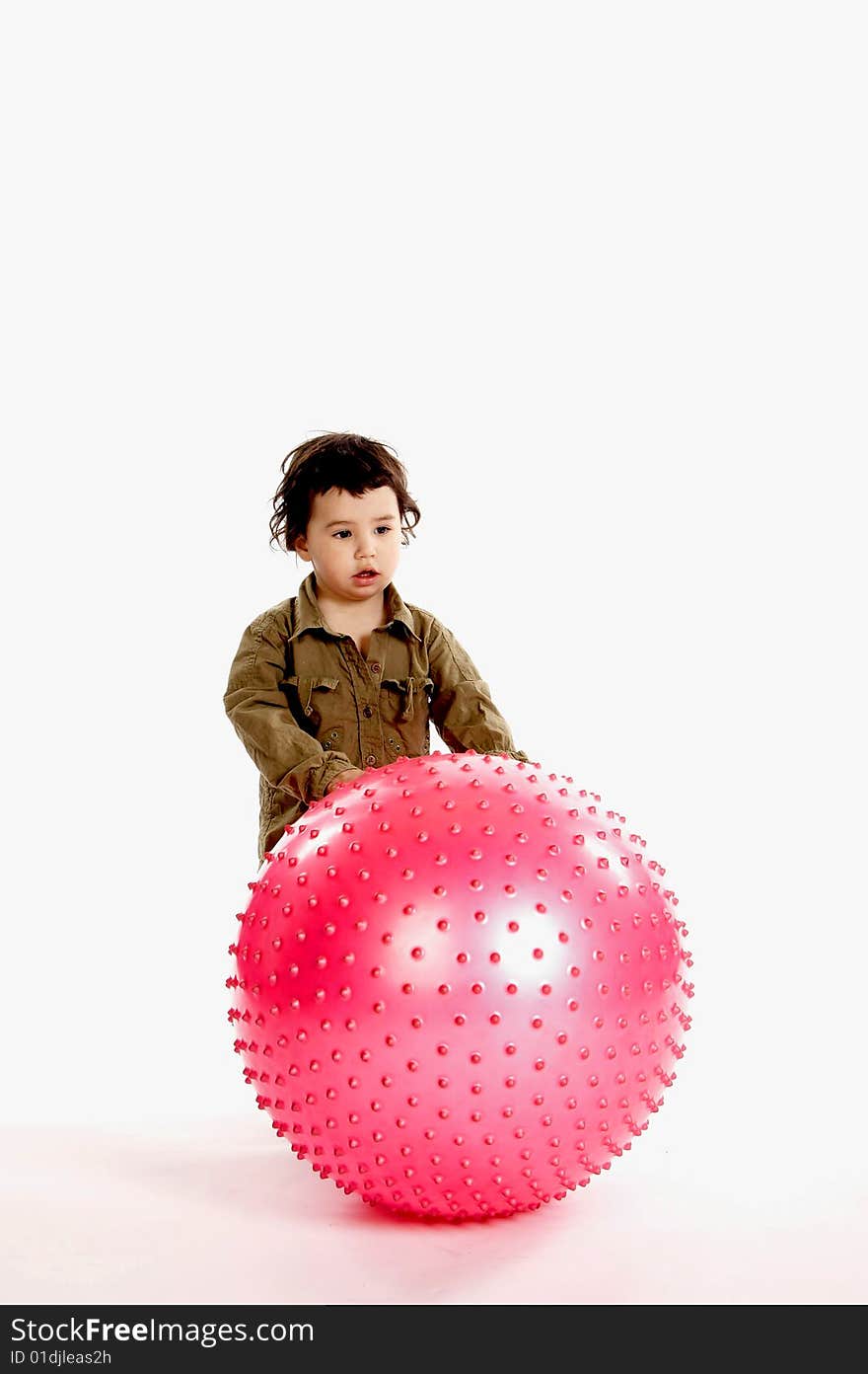 A little boy plays with a big pink ball. A little boy plays with a big pink ball