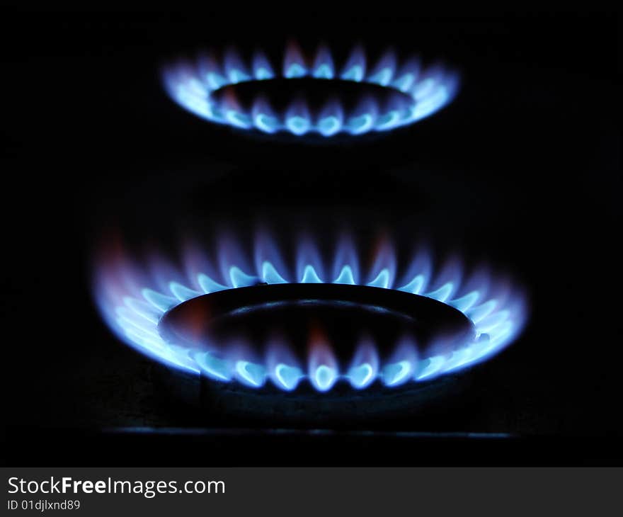 Blue flame of gas over black background