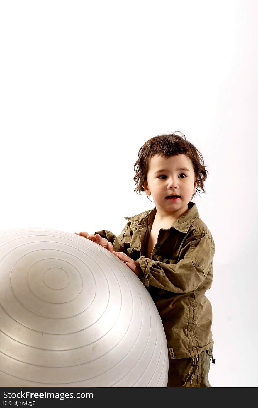 Little boy plays with a big silver ball in photo studio