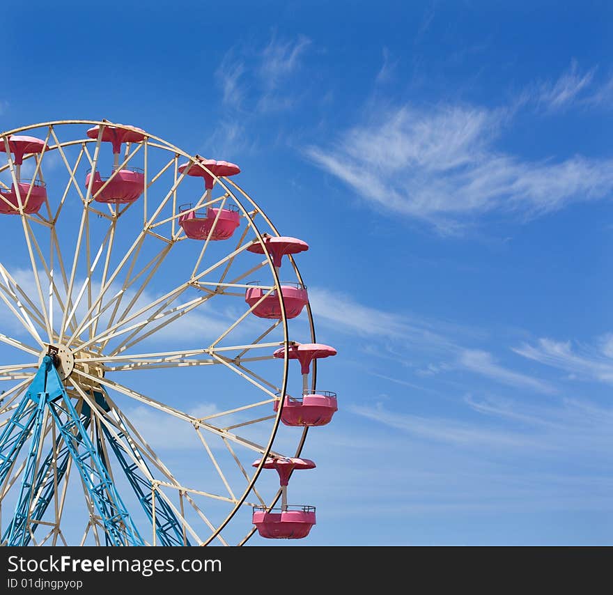 Ferris wheel against a blue sky with space for text