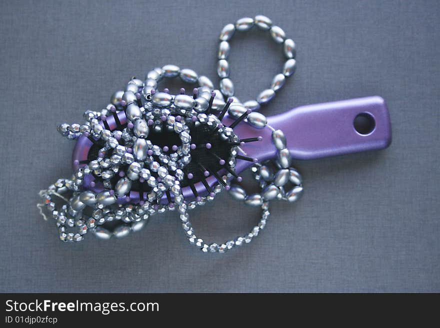 Hairbrush and necklace entwined lying on a table top