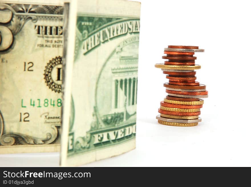 Five dollar paper money and column of coins isolated on the white background.