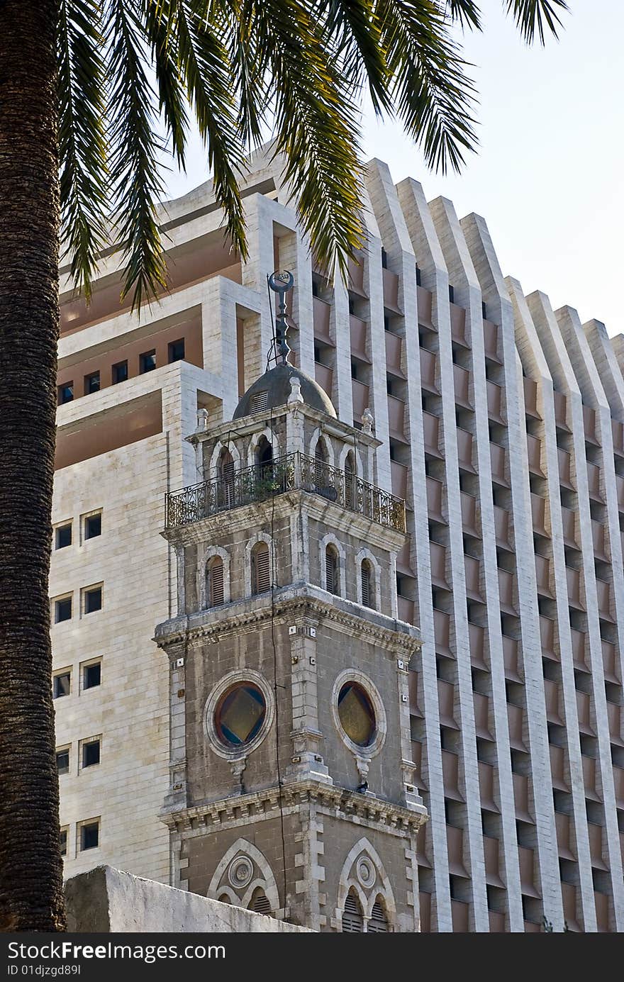 Old minaret on the high modern building background in Haifa city. Old minaret on the high modern building background in Haifa city.