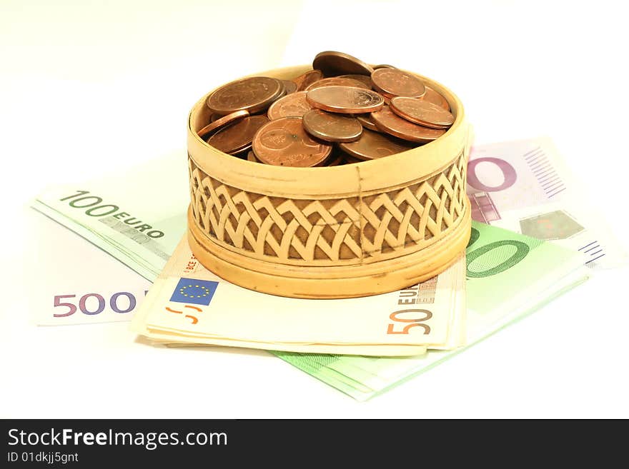 Carved wooden box full of coins on banknotes of euro, isolated on a white