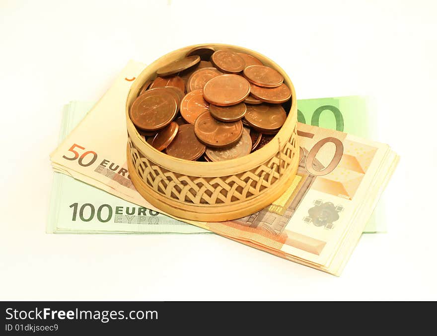 Carved wooden box full of coins on banknotes of euro, isolated on a white