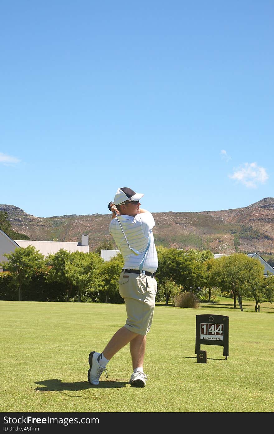 Young male golfer hitting the ball from the fairway on a beautiful summer day. Young male golfer hitting the ball from the fairway on a beautiful summer day