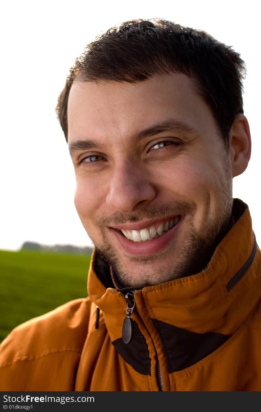 Smiling man in orange jacket on white sky background