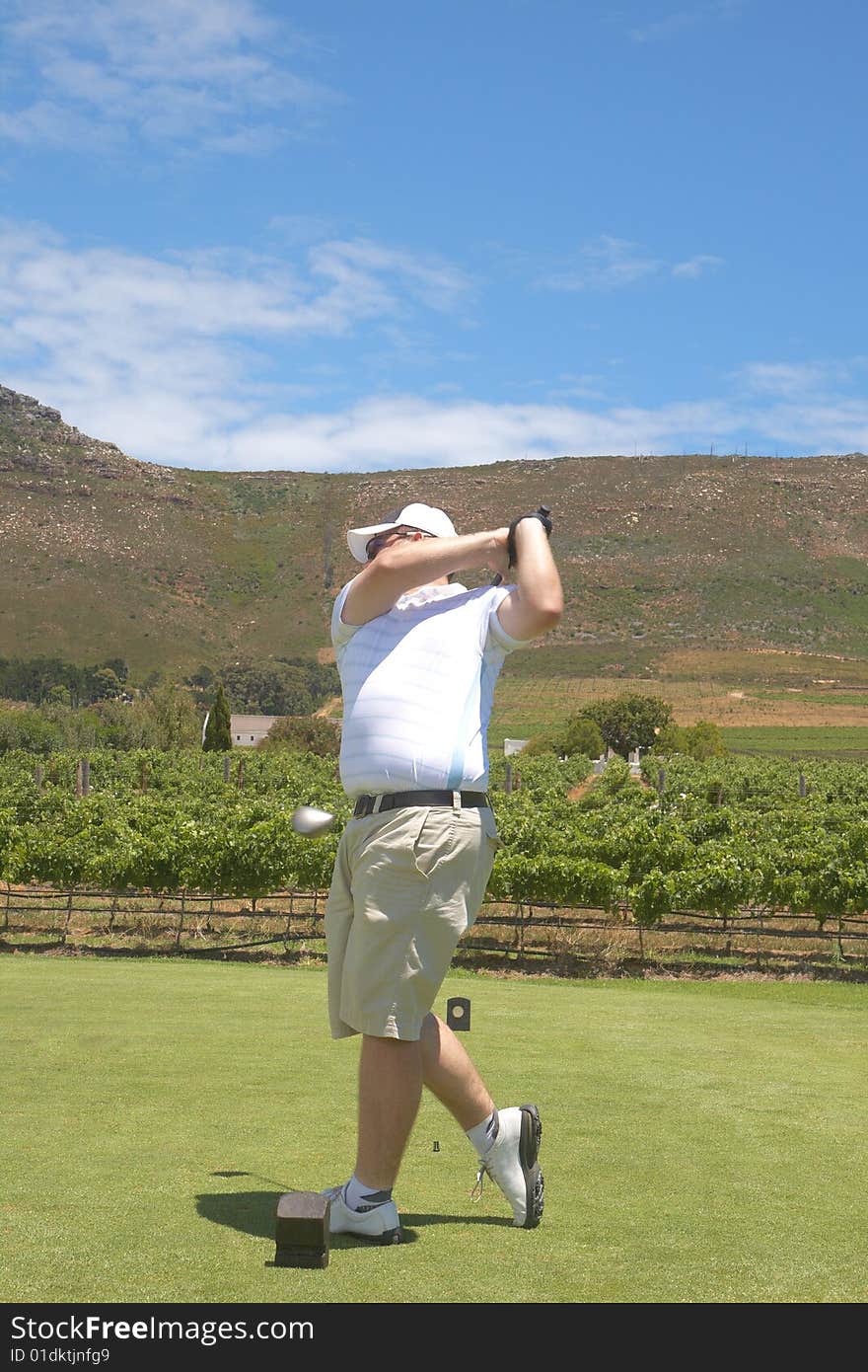 Young male golfer hitting the ball from the fairway on a beautiful summer day. Young male golfer hitting the ball from the fairway on a beautiful summer day