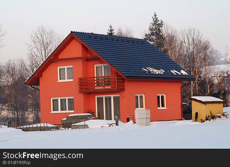 Red colored house with black roof in winter. Red colored house with black roof in winter