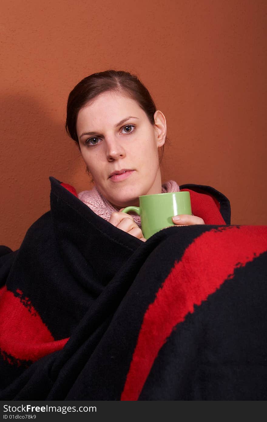 A young sick woman with a cup of tea in her hand. A young sick woman with a cup of tea in her hand.