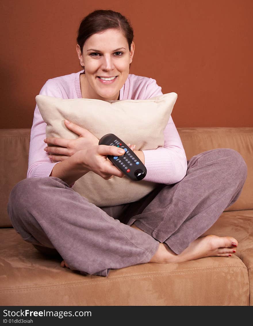 A young woman sits in front of a TV with the remote control in her hand on a couch. A young woman sits in front of a TV with the remote control in her hand on a couch.