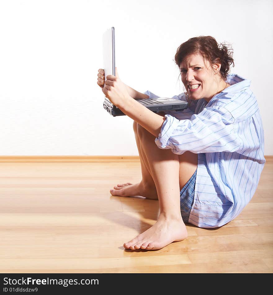 A young woman at home with her laptop sitting on the floor in her new appartment. She seems to be very frustrated. A young woman at home with her laptop sitting on the floor in her new appartment. She seems to be very frustrated.