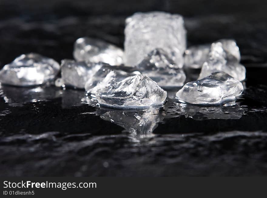 Ice melting on black slate with reflection