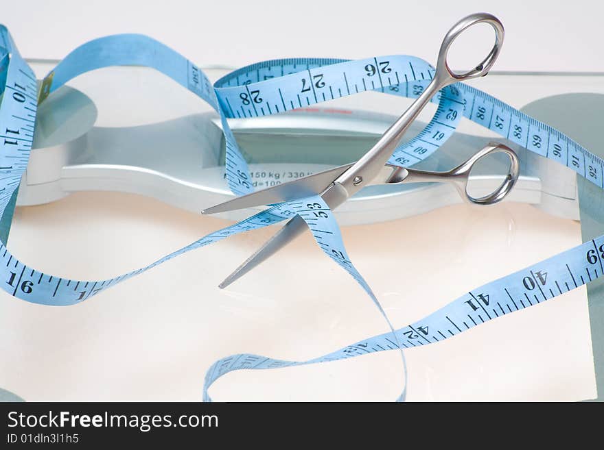 Concept image of scissors cutting tape measure symbolizing weight lost. Concept image of scissors cutting tape measure symbolizing weight lost