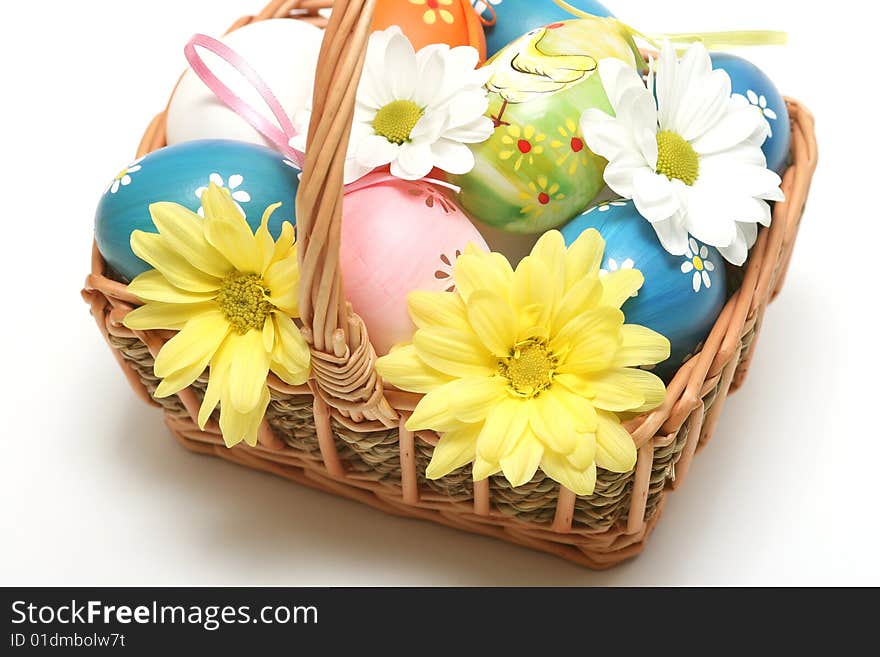 Easter basket with easter eggs and flower on vhite background.