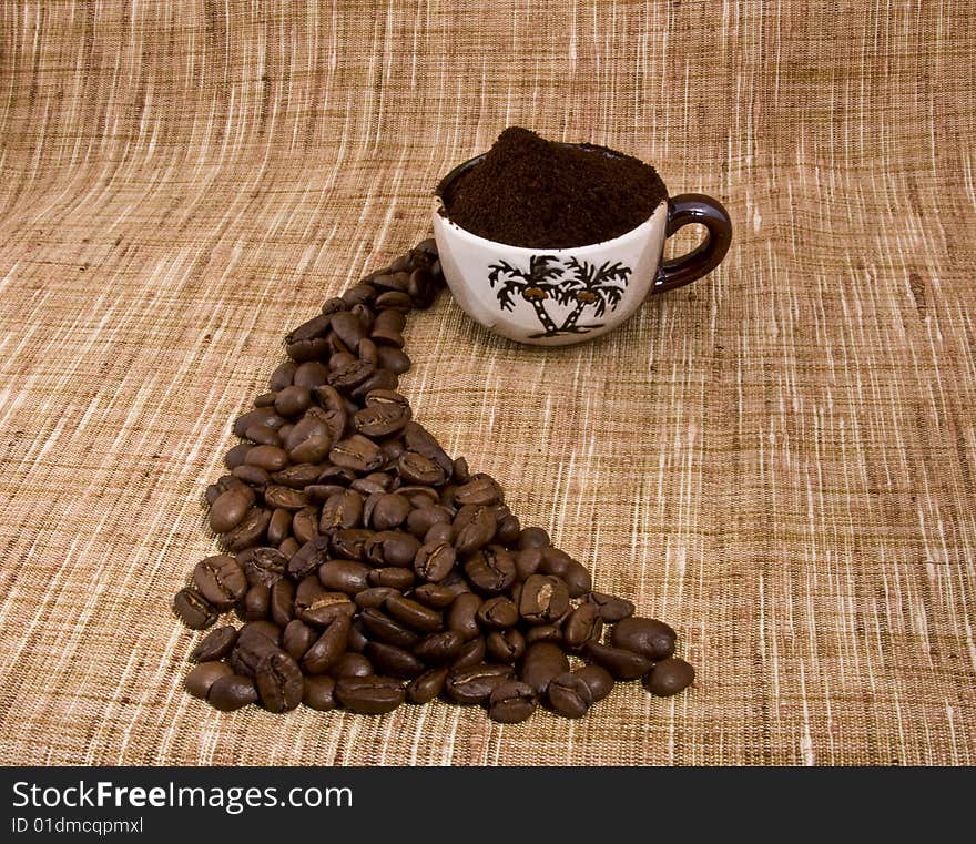 Coffee beans and cup close-up isolated on a beige sacking