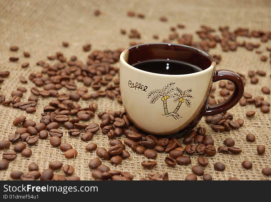 Cup with coffee. Fried beans at background