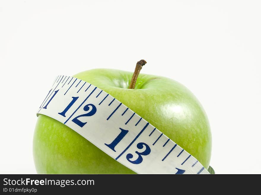 a juicy green apple wrapped by a measuring tape isolated on white.  shot up close and intentionally off centered.