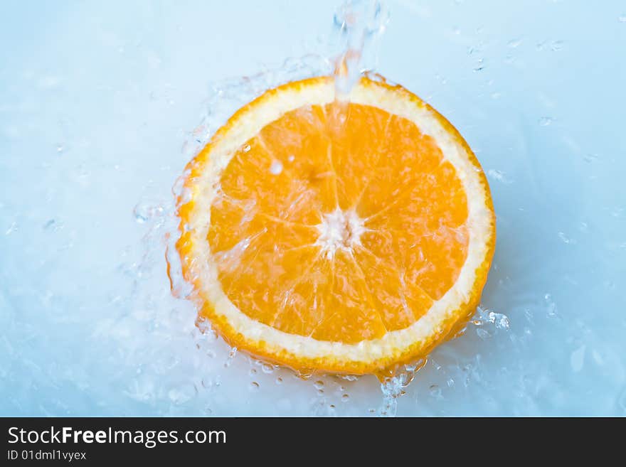 Blue water pouring over half orange