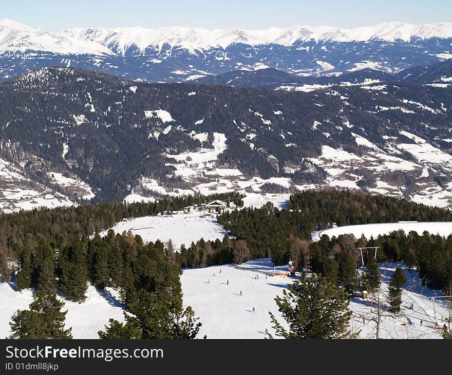 Snowy Mountains with trees and skiers