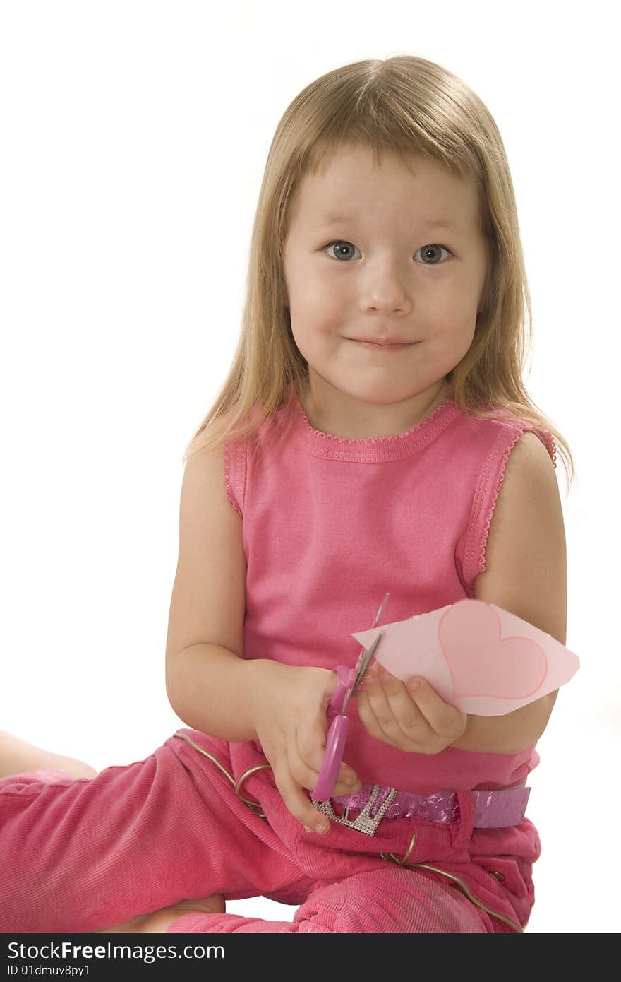 Pretty small girl in red is cutting paper heart shape