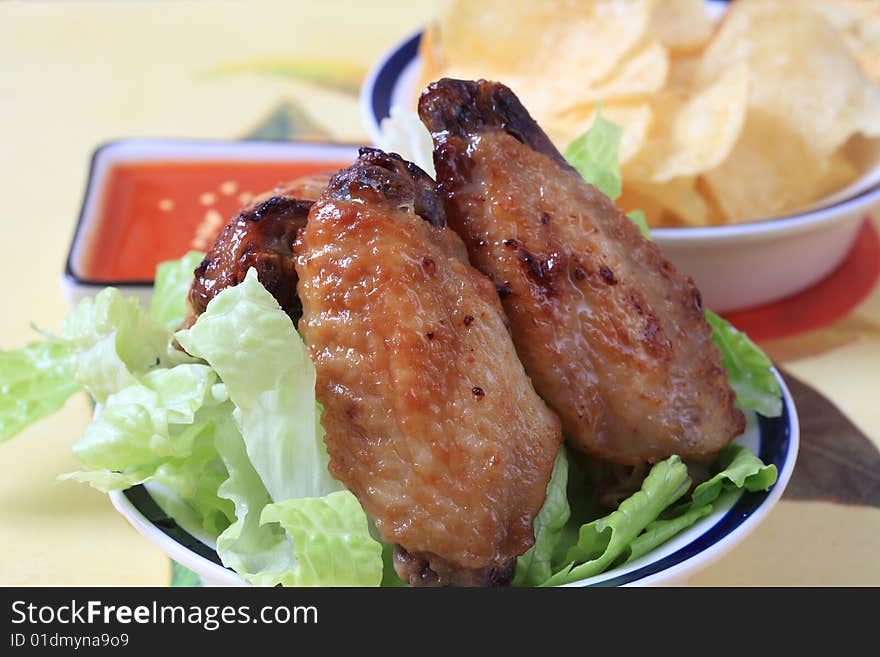 Grilled chicken wings with hot pepper sauce and salad