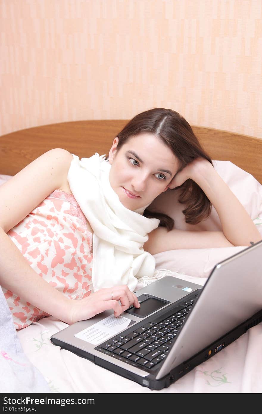 Girl with a sick throat lays in bed with laptop