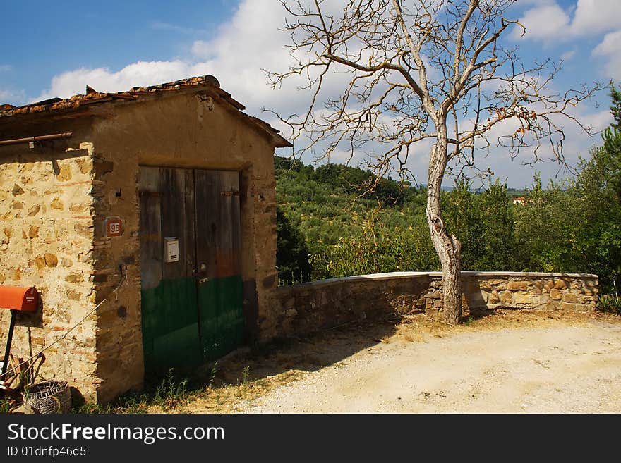 Tuscany country scene with hill on the background, tree and garage on the foreground